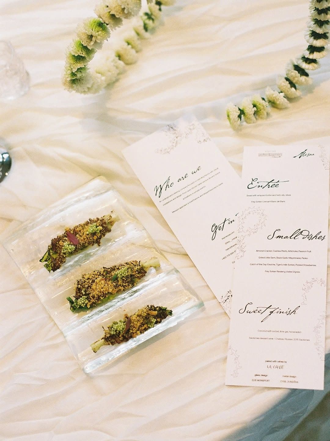 Menu cards and a plated course on white linen